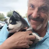 Bruce holding his Mini Pomsky puppy, Boots, shortly after bringing him home